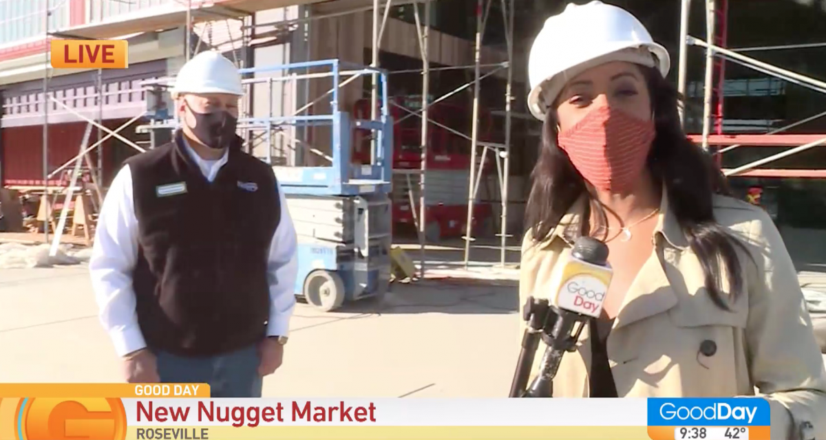 reporter and store director standing outside new Nugget Markets under construction